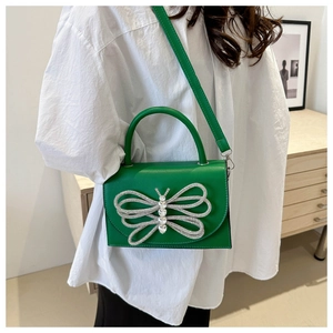 Detalle del bolso bandolera de cuero PU verde con un adorno de mariposa con diamantes