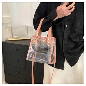 Close-up of pink faux leather trim and sturdy metal rivets on a transparent PVC tote bag