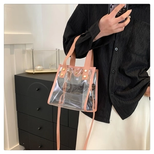 Close-up of a pink transparent PVC beach bag with rivets and inner pouch on a model