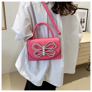 Detalle de bolso rosa con un gran lazo de pedrería y textura de cuero sintético suave