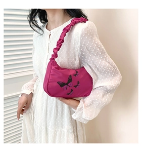 Detail of rose red shoulder bag with butterfly print and ruched strap on model
