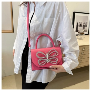 Detalle del bolso bandolera de cuero rosa con un lazo de mariposa de diamantes de imitación