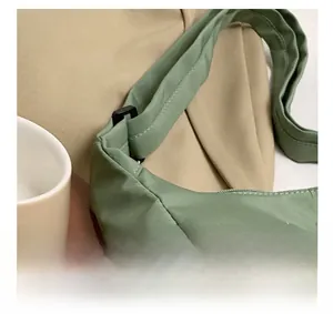 Detailed close-up of the green nylon tote bag with adjustable buckle and metal zipper