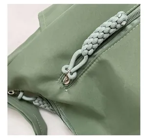 Detail of the green nylon tote bag featuring a durable woven rope zipper pull design