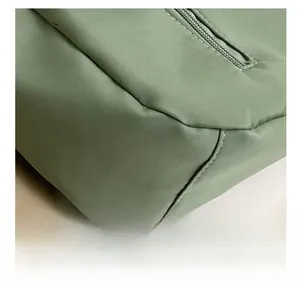 Macro detail of high-quality stitching and smooth zipper closure on green nylon tote bag