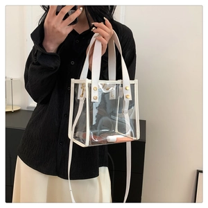 Detailed view of transparent PVC beach bag with white leather trim and gold metal rivets