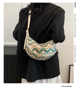 Detail of colorful striped woven crescent bag with leather strap on a model shoulder