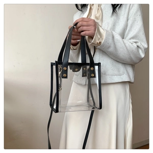 Detail of transparent PVC tote bag with black leather trim and golden metal rivets