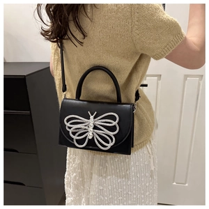 Detalle del bolso bandolera negro con una gran mariposa de diamantes de imitación plata