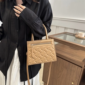 Elegant khaki woven texture handbag with shoulder strap shown in minimalist interior setting