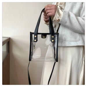 Detail of transparent PVC beach bag with black faux leather trim and gold metal rivets