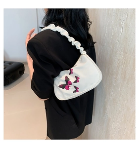 White nylon shoulder bag with pink butterfly prints and ruffled cloud-style strap shown on model