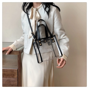 Close-up of transparent beach bag featuring black leather trim and gold rivet hardware