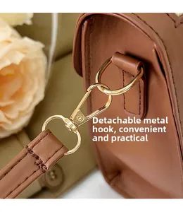 Close-up of detachable golden hardware hook and leather strap with fine stitching