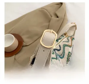 Detail of woven wave pattern handbag showing gold buckle and cream leather strap