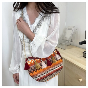 Close-up of bohemian woven crossbody bag with colorful tassels and golden chain strap