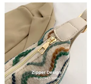 Detail of golden zipper and colorful embroidered tweed texture on woven shoulder bag