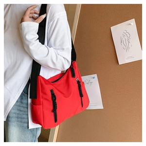 Détail du sac fourre-tout rouge avec fermetures éclair et large bandoulière noire