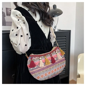 Detailed shot of ethnic knit shoulder bag with vibrant colorful tassels and gold chain