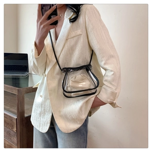 Detail of transparent PVC crossbody bag with cream drawstring pouch and black strap