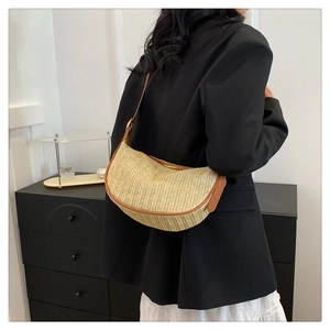 Detail of hand-woven straw shoulder bag with brown leather trim and crescent shape