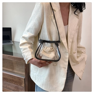 Detailed view of a clear PVC bucket bag with cream canvas insert and slim black strap