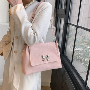 Pink shoulder bag with silver bow accent and chain strap worn by a female model