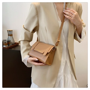 Detail of brown PU leather crossbody bag with gold text and adjustable shoulder strap