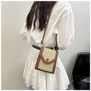 Detail of straw woven crossbody bag with brown leather trim and adjustable shoulder strap