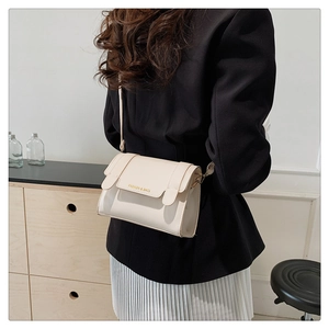 Detailed back view of a cream-colored leather handbag worn by a model in a minimal setting