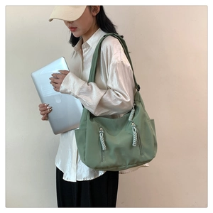 Detail of green canvas tote bag featuring dual vertical zippers and woven pullers