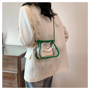 Detail of transparent PVC tote with green trim and drawstring inner bag on model