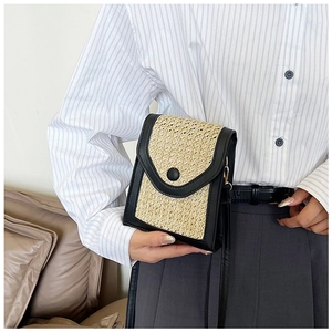 Detailed view of straw-woven crossbody phone bag with black leather trim and snap button