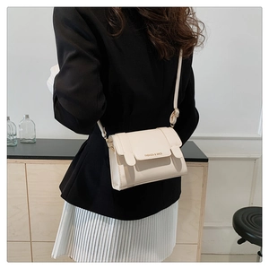 Close-up of cream square crossbody bag featuring metal accents and thin shoulder strap