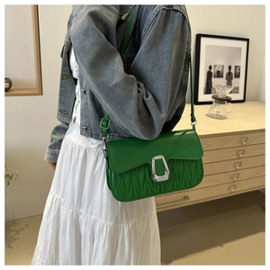 Détail du sac à bandoulière matelassé vert avec fermoir argenté porté par un mannequin