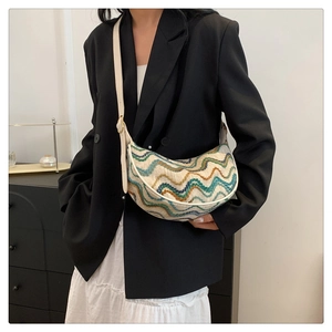 Close-up of knit wave pattern and leather trim on minimalist half-moon crossbody bag