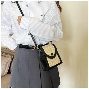 Detail of a black leather and straw woven crossbody bag with adjustable strap on model
