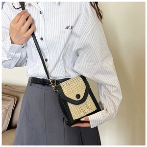 Detail of woven straw phone bag with black leather trim and magnetic closure