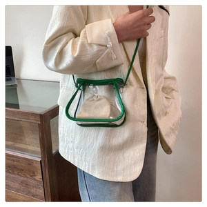 Detail of transparent PVC mini crossbody bag with green leather trim on beige blazer
