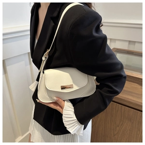 Detail of a minimalist white baguette bag featuring a gold buckle and elegant curved design