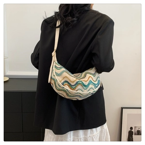Detail of adjustable leather strap and colorful wavy knit texture on the crescent bag