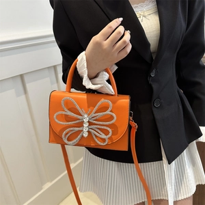 Bolso bandolera de moda naranja brillante con una gran mariposa de pedrería plateada
