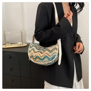 Detailed knit texture of a multi-color striped hobo bag worn by a model in a black blazer