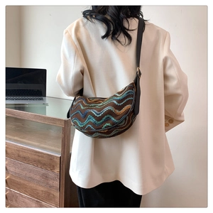 Detail of a brown woven crescent bag with colorful zigzag embroidery and leather strap