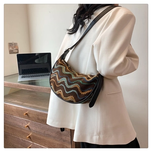 Detail of colorful embroidered wave pattern and black leather strap on a hobo bag