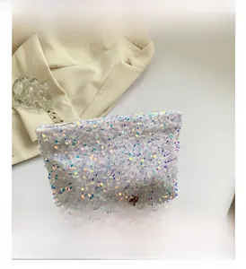 Close-up of white iridescent sequin clutch bag with metal zipper on beige suit