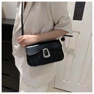 Détail du sac à bandoulière noir matelassé avec plis verticaux et boucle en métal argenté