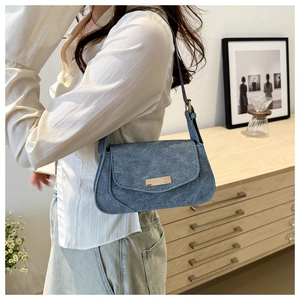 Blue matte shoulder bag with gold trim shown in a stylish minimalist lifestyle setting
