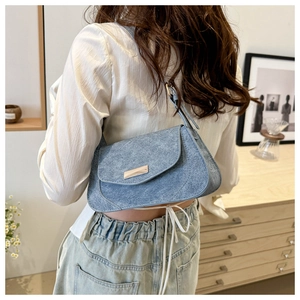 Model wearing light blue suede baguette bag with silver buckle in a minimalist interior