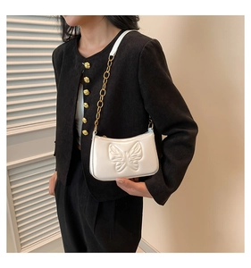 Détail du sac blanc en cuir brillant avec relief papillon 3D et chaîne dorée